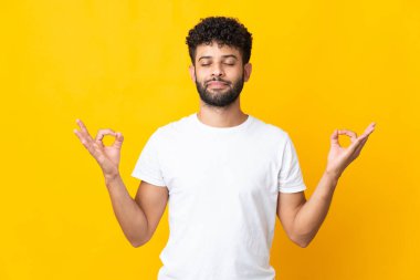 Genç Faslı adam, sarı arka planda izole edilmiş, zen pozisyonunda.