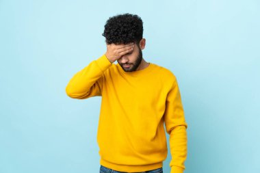 Faslı genç bir adam mavi arka planda başağrısı ile izole edilmiş.