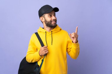 Spor çantalı genç Faslı adam mor arka planda izole edilmiş harika bir fikre işaret ediyor.