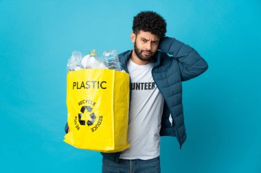 Genç Faslı bir adam, izole edilmiş arka plan üzerinde geri dönüşüm yapmak için plastik şişelerle dolu bir çanta tutuyor.