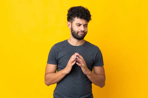 Young Moroccan man isolated on yellow background scheming something