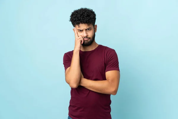 Young Moroccan man isolated on blue background thinking an idea