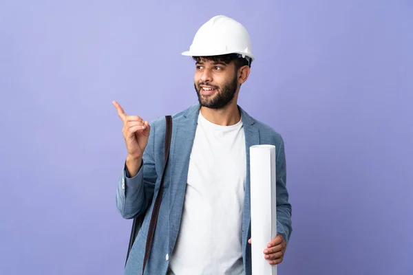 Young architect Moroccan man with helmet and holding blueprints over isolated background intending to realizes the solution while lifting a finger up