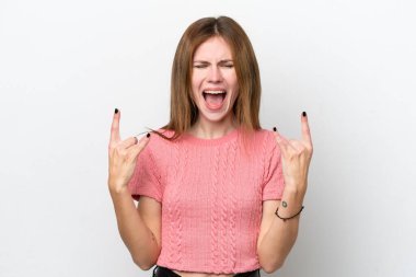 Beyaz arka planda izole edilmiş genç bir İngiliz kadın boynuz hareketi yapıyor.