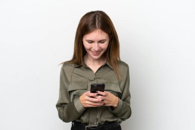 Beyaz arka planda izole edilmiş genç bir İngiliz kadın cep telefonuyla mesaj gönderiyor.