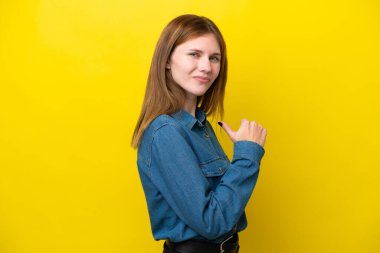 Sarı arka planda soyutlanmış genç bir İngiliz kadın gururlu ve kendini beğenmiş.