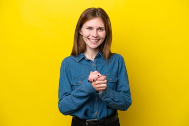 Sarı arka planda yalnız yaşayan genç İngiliz kadın gülüyor.