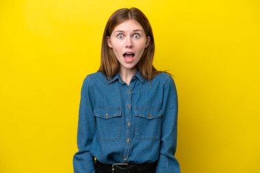 Sarı arka planda yalıtılmış genç bir İngiliz kadın. Sürpriz bir yüz ifadesi var.