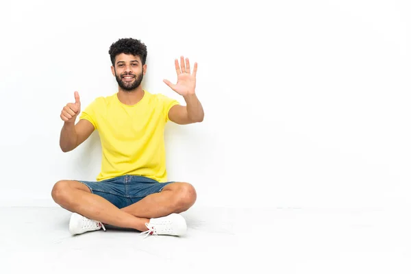 Joven Hombre Guapo Marroquí Sentado Suelo Sobre Fondo Aislado Contando — Foto de Stock