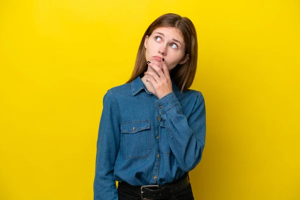 Young English woman isolated on yellow background having doubts