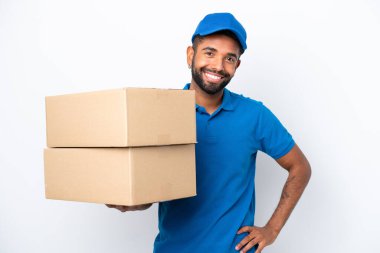 Teslimatçı Brezilyalı adam beyaz arka planda izole edilmiş. Kolları kalçasında ve gülümsüyor.