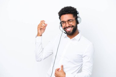 Tele pazarlamacı Brezilyalı adam beyaz arka planda izole edilmiş bir kulaklıkla gitar jesti yapıyor.