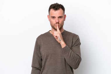 Beyaz arka planda izole edilmiş genç Brezilyalı bir adam sessizlik işareti gösteriyor. Parmağını ağzına sokuyor.