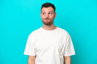Genç Brezilyalı bir adam mavi arka planda izole edilmiş.
