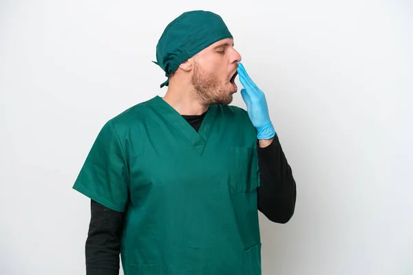 身穿绿色制服的巴西外科医生 背景为白色 打呵欠 双手捂住宽大张开的嘴 — 图库照片