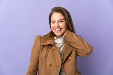 Orta yaşlı Brezilyalı kadın, mor arka planda yalnız gülüyor.