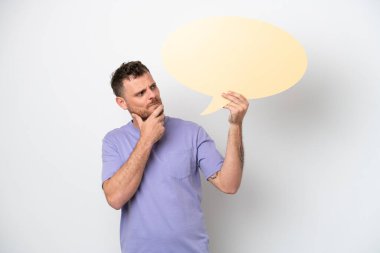 Beyaz arka planda izole edilmiş genç Brezilyalı bir adam boş bir konuşma balonu tutuyor ve düşünüyor.