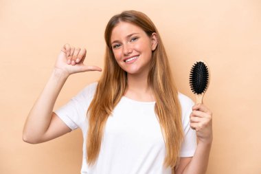 Saçları taranmış genç, güzel sarışın kadın bej arka planda yalnız gururlu ve kendinden memnun.