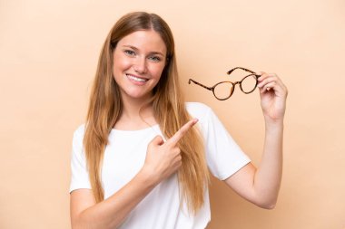 Bej arka planda gözlüklü, sarışın, güzel bir kadın.