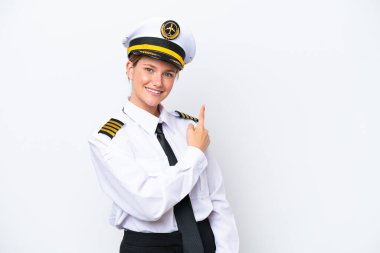 Beyaz arka planda izole edilmiş Kafkasyalı uçak pilotu bir ürün sunmak için kenarı işaret ediyor.