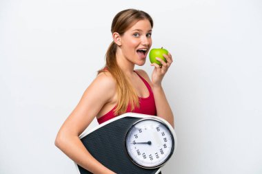 Beyaz arka planda izole edilmiş, tartı makinesi ve elmasıyla genç, güzel sarışın bir kadın.