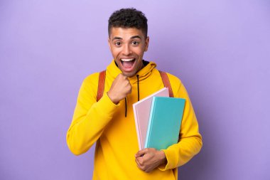 Mor arka planda izole edilmiş Brezilyalı genç bir adam zaferi kutluyor.