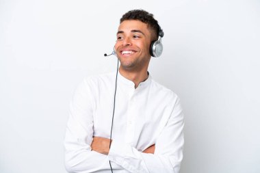 Tele pazarlamacı Brezilyalı adam kulaklıkla çalışıyor. Beyaz arka planda izole edilmiş mutlu ve gülümsüyor.