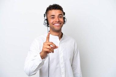 Tele pazarlamacı Brezilyalı adam beyaz arka planda izole edilmiş bir kulaklıkla çalışıyor ve parmağını kaldırıyor.