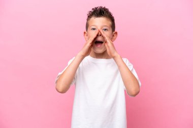 Little caucasian boy isolated on pink background shouting and announcing something