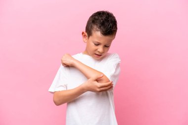 Küçük beyaz çocuk pembe arka planda izole edilmiş, dirseğinde ağrı var.