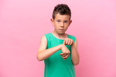 Pembe arka planda izole edilmiş küçük beyaz çocuk geç kalma jesti yapıyor.