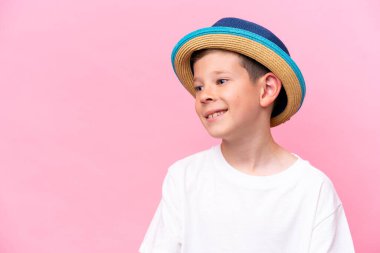 Pembe arka planda izole edilmiş şapka takan beyaz bir çocuk.