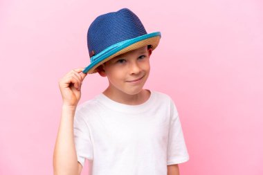 Pembe arka planda izole edilmiş şapka takan beyaz bir çocuk.