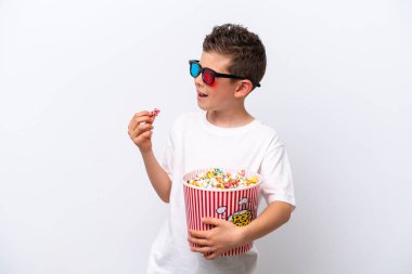 Beyaz arka planda üç boyutlu gözlüklü ve elinde koca bir kova patlamış mısır tutan beyaz tenli bir çocuk.