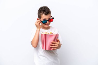 Beyaz arka planda üç boyutlu gözlüklü ve elinde koca bir kova patlamış mısır tutan beyaz tenli bir çocuk.