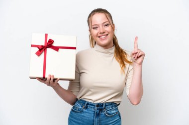 Beyaz arka planda izole edilmiş bir hediye taşıyan beyaz bir kadın harika bir fikre işaret ediyor.