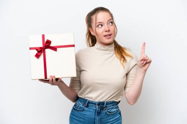 Beyaz arka planda izole edilmiş bir hediye tutan genç beyaz kadın çözümü fark etmek için parmağını kaldırıyor.