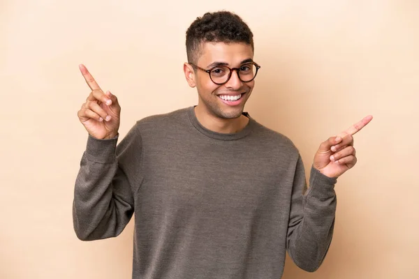 Young Brazilian Man Isolated Beige Background Pointing Finger Laterals Happy — Fotografia de Stock