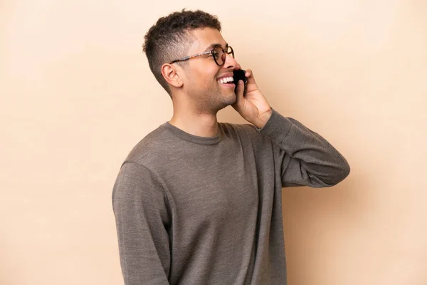 Young Brazilian Man Isolated Beige Background Keeping Conversation Mobile Phone — Stock fotografie