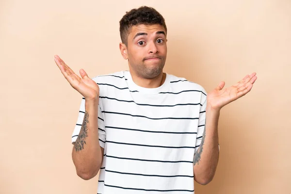 Young Brazilian Man Isolated Beige Background Making Doubts Gesture — Stok fotoğraf