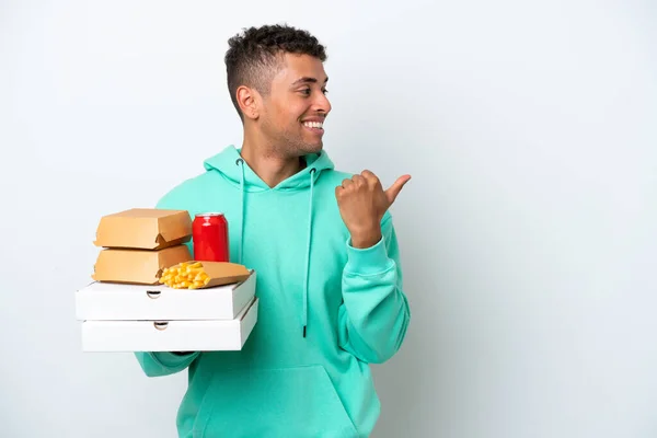 Young Brazilian Holding Fast Food Isolated White Background Pointing Side — Φωτογραφία Αρχείου