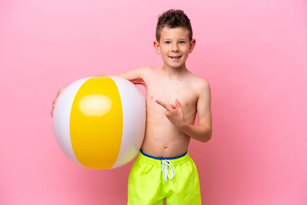Little Caucasian Boy Holding Beach Ball Isolated Pink Background Pointing — Stockfoto