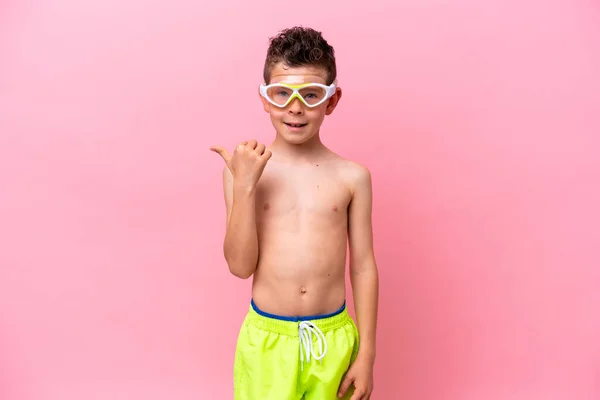 Mały Biały Chłopiec Okularach Nurkowych Odizolowany Różowym Tle Wskazując Bok — Zdjęcie stockowe