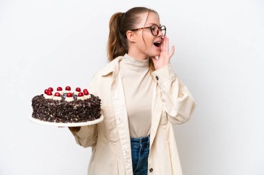Beyaz arka planda izole edilmiş bir doğum günü pastası tutan beyaz bir kadın ağzı sonuna kadar açık bağırıyor.