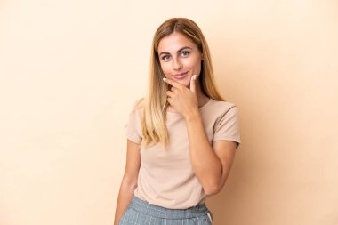 Sarışın Uruguaylı kız bej arka planda izole edilmiş.