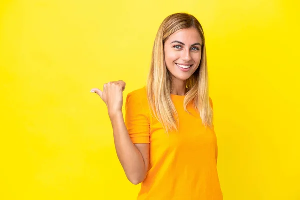 Chica Uruguaya Rubia Aislada Sobre Fondo Amarillo Apuntando Hacia Lado — Foto de Stock