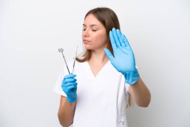 Beyaz arka planda izole edilmiş aletleri tutan dişçi kadın dur hareketi yapıyor ve hayal kırıklığına uğruyor