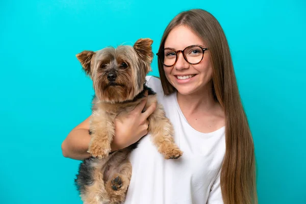 Young Lithuanian woman holding a dog isolated on blue background