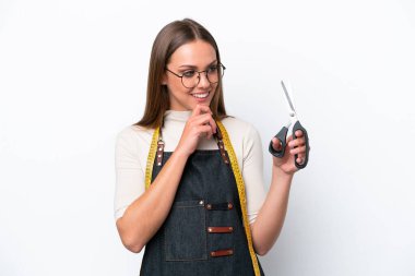 Young seamstress woman isolated on white background looking to the side and smiling