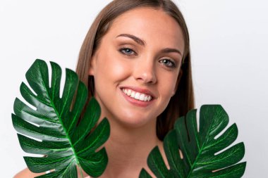 Beyaz arka planda izole edilmiş beyaz bir kadın elinde mutlu bir ifadeyle bir palmiye yaprağı tutuyor. Portreyi kapat